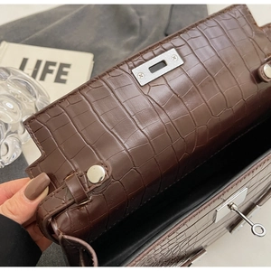 Detail of dark brown crocodile embossed leather with silver metal twist-lock on bag