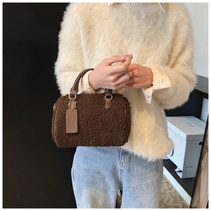 Dettaglio borsa Boston in peluche marrone scuro con manici in pelle e dettagli metallici oro