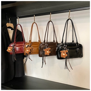 Detailed view of four retro patent leather shoulder bags with cute bear charms in various colors