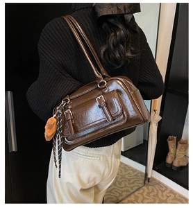 Detail of vintage brown shoulder bag with pocket buckles and plush bear charm