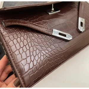 Detailed close-up of dark brown crocodile embossed leather and silver metal clasp lock