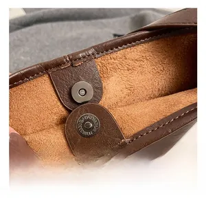 Macro shot of metal magnetic buckle and textured brown leather on a winter tote bag