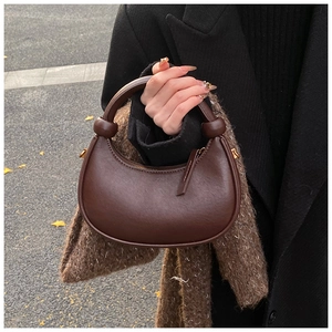 Detailed view of the dark brown crescent bag with a decorative knot on the leather handle