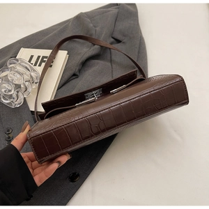Detail of brown crocodile pattern shoulder bag featuring silver buckle and leather texture