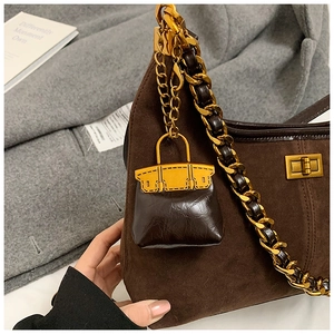 Details der kaffeebraunen Wildledertasche mit goldener Kette und Mini-Taschenanhänger