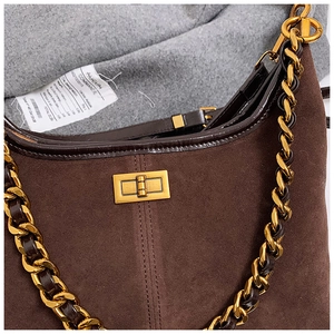 Nahaufnahme der braunen Wildleder-Beuteltasche mit goldenem Drehverschluss und Kette