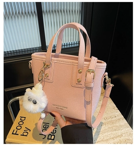 Pink lychee texture bucket bag detail with gold hardware and white plush keychain