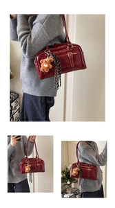 Detail view of burgundy patent leather Boston bag with bear charm and silk scarf trim