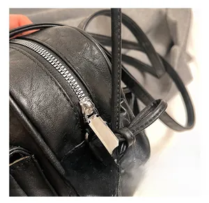 Close-up of polished silver metal zipper and textured black leather grain on Boston bag