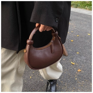 Detail of dark brown leather crescent bag with unique knot design on the handle