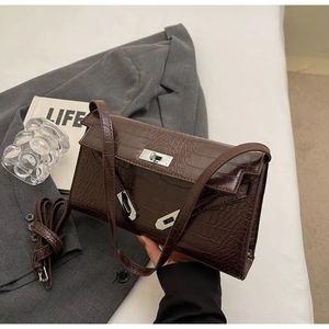 Detail of dark brown crocodile pattern handbag featuring a silver twist lock and strap