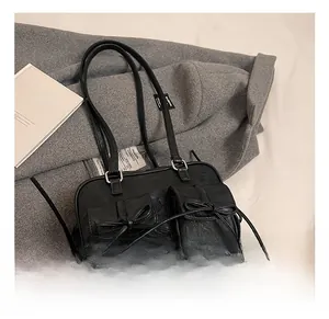 Detail of black leather shoulder bag with decorative bows and silver metal hardware