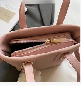 Detailed shot of a smooth gold zipper on a pink suede bucket bag with internal pockets