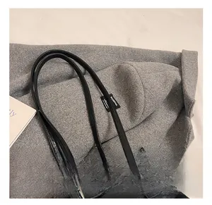 Close-up of black leather underarm bag with double slim straps and silver metal buckles