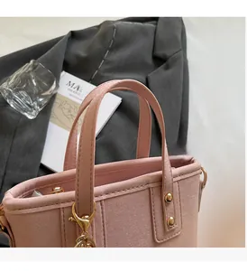 Close-up of pink suede bucket bag handles with light gold hardware and durable stitching