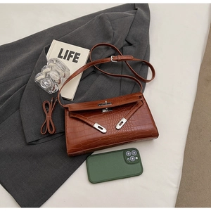Detail of brown crocodile pattern leather shoulder bag with silver clasp on grey blazer