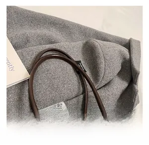 Detail view of thickened round handles and silver rings on dark brown leather boston bag