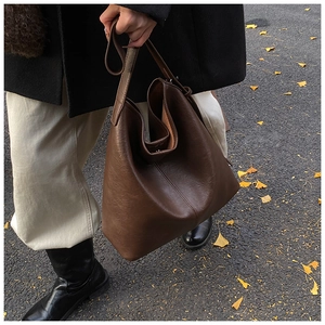 Detail of deep brown leather tote bag showing large capacity and minimalist seam texture