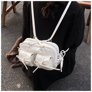 Detail showing white glossy PU Boston bag with 3D bow pockets and silver zipper on model