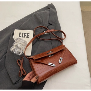 Detail of brown crocodile pattern shoulder bag with silver clasp on a grey suit