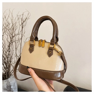 Detail of a beige and brown mini crossbody bag with golden dual zippers and hardware