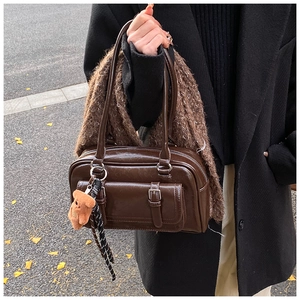 Detail of dark brown vintage Boston bag featuring retro PU leather texture and plush bear charm