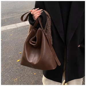 Detail of a large dark brown leather tote bag with soft lychee grain texture in autumn style