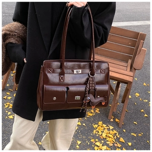 Detail of dark brown vintage briefcase bag with silver locks on an autumn park bench