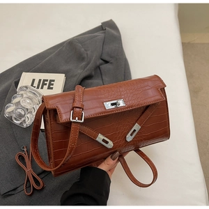 Detail of a brown crocodile pattern leather bag with silver lock and shoulder strap