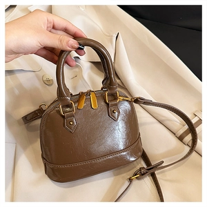 Detail of dark brown crackle texture leather mini bag with gold hardware and top handle