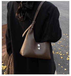 Borsa a spalla in pelle marrone a mezzaluna indossata con un cappotto di lana nero in autunno