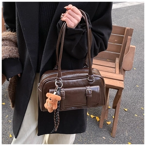 Detail of dark brown vintage Boston bag with oil wax texture and bear charm detail