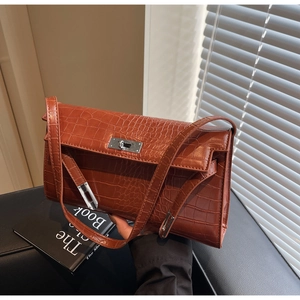 Detail of crocodile embossed leather texture and silver buckle on brown shoulder bag