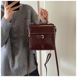 Mirror selfie showing the shiny burgundy leather handbag with silver buckle and handle
