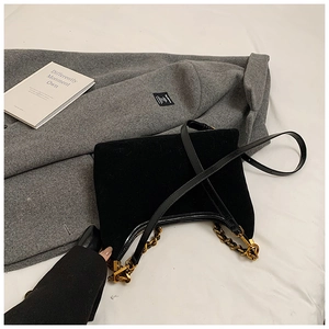 Detail der schwarzen Wildleder-Beuteltasche mit goldener Kette und Leder-Schultergurt