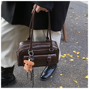 Detail of vintage brown oil-wax leather Boston bag with plush bear charm and buckle