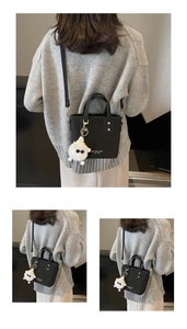 Detail view of black lychee grain leather bucket bag with plush charm and shoulder strap
