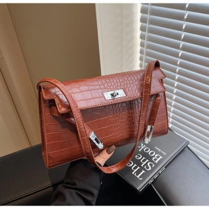 Detail of brown crocodile pattern shoulder bag with a silver rotating lock and flap