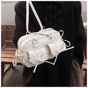 Detail of cream Boston bag with bow-knot pockets and silver hardware on a shoulder strap