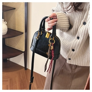 Detail of black shell-shaped handbag with wax-texture leather and gold hardware