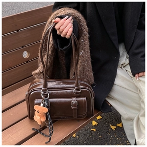 Detail of dark brown vintage faux leather boston bag with a cute bear plush keychain