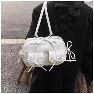 Detail of a creamy white Boston bag with oversized bow accents and textured faux leather