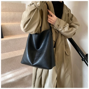Detailed texture of black leather tote bag worn by model on a minimalist staircase