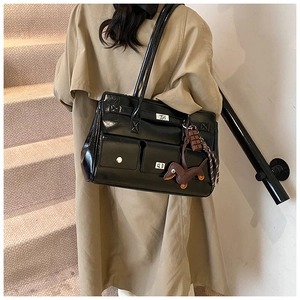 Close-up of black patent leather bag with silver twist locks and dog-shaped charm