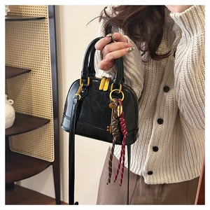 Detail of black shell handbag with pleated leather texture and gold hardware accents