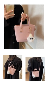 Detailed view of a pink bucket bag with a white plush monster charm and brand lettering