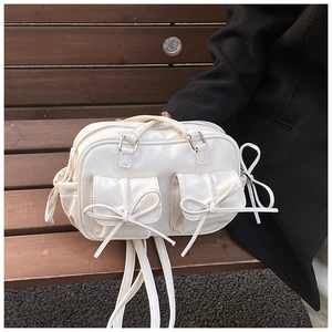 Detail of cream white PU backpack with bow knots on a wooden bench in a lifestyle setting