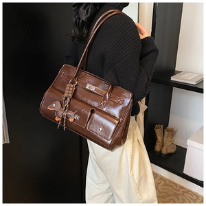 Detail of dark brown glossy leather tote bag with multi-pockets and a cute dog charm