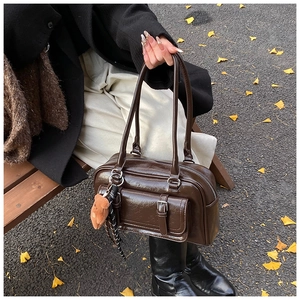 Detail of dark brown retro leather handbag with metal buckle and plush bear charm
