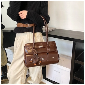 Close-up of vintage brown tote bag with metal buckles and dog pendant on shoulder